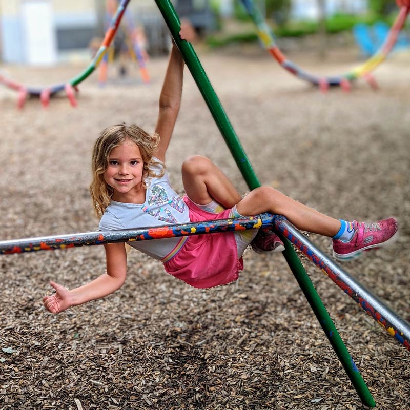 A girl plays on the jungle gym at the Community School campus playground.