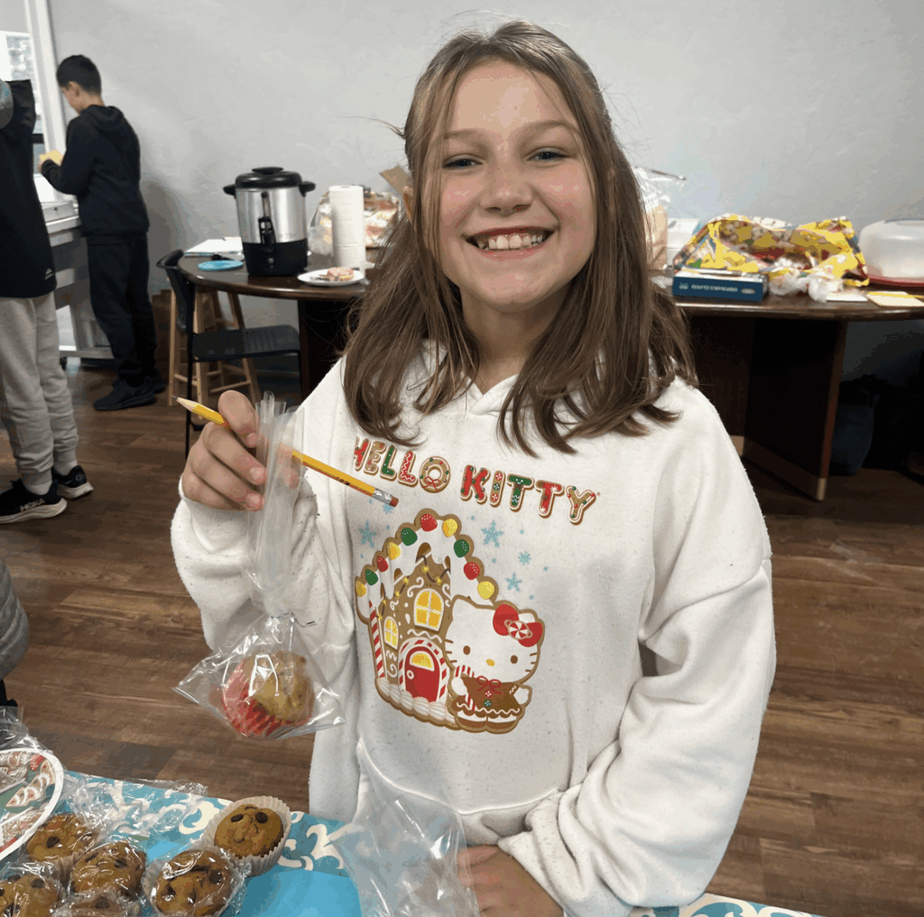 A student is smiling and holding up a muffin.