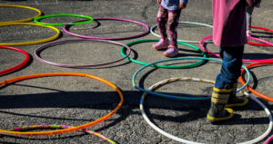 Hula hoops on the ground with kids lower body jumping in the circles.