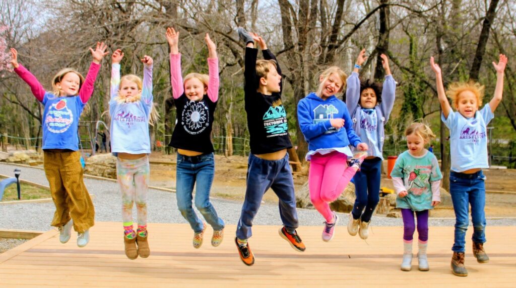 CS students joyously jump while wearing CS shirts.